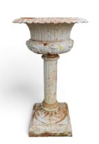 A white cast iron garden urn on square pedestal.