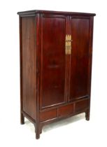 A modern Chinese wooden cabinet, with brass lock, twin panelled doors enclosing shelves and two