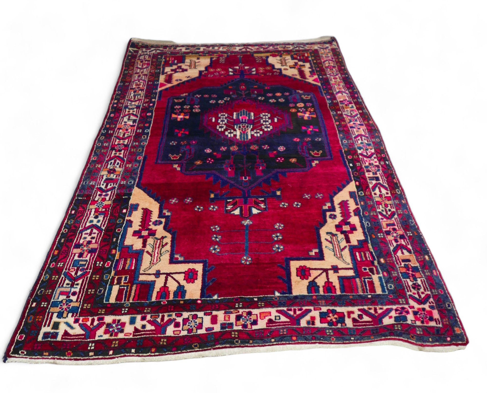 A Persian rug, with red ground and geometric floral decoration, central blue medallion with