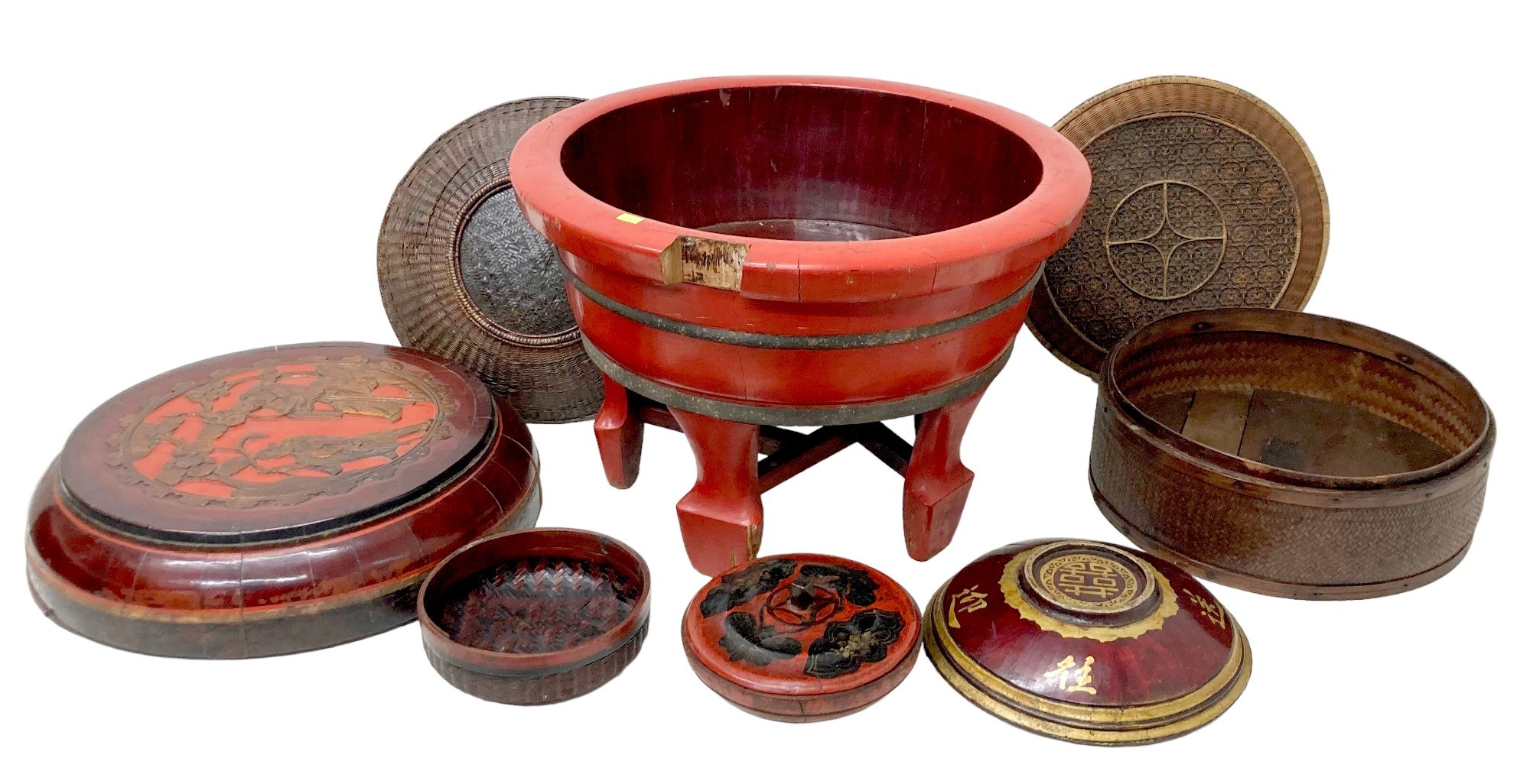 A collection of eight Chinese wooden and rattan bowls, the largest painted red and raised on four