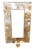 A modern brass effect mirror with cheese plant leaf border, rectangular.