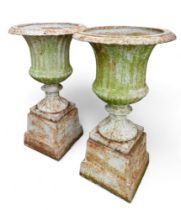 A pair of cast iron fluted garden urns on pedestals with square bases. (2)