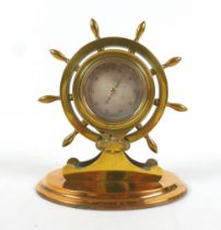 A brass ships wheel desk barometer, 17cm by 11cm by 20cm tall.