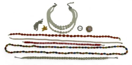A collection of costume jewellery, comprising brooches and necklaces, including an amber bead
