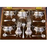 An Edwardian silver seven piece cruet set, pepper 8.7cm high, with five spoons, Henry Matthews,