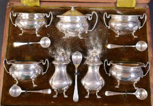 An Edwardian silver seven piece cruet set, pepper 8.7cm high, with five spoons, Henry Matthews,