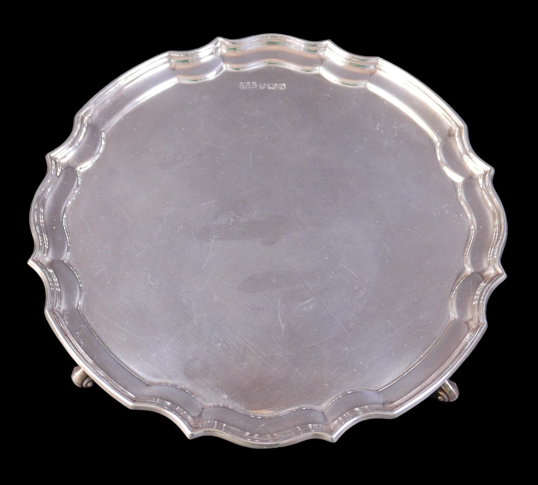 An Elizabeth II silver salver tray, with Chippendale pie-crust rim, raised upon three scroll feet,