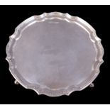 An Elizabeth II silver salver tray, with Chippendale pie-crust rim, raised upon three scroll feet,