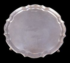 An Elizabeth II silver salver tray, with Chippendale pie-crust rim, raised upon three scroll feet,