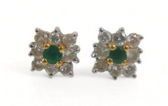 A pair of diamond and emerald flowerhead earrings, each comprising eight brilliant cut diamonds