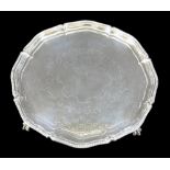 A George V silver tray, with decorative scalloped edge, engraved centre, raised on three ball and