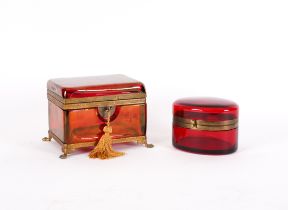 A FRENCH OR BOHEMIAN RUBY TINTED GLASS AND GILT-METAL MOUNTED CASKET AND AN OVAL EXAMPLE (2)