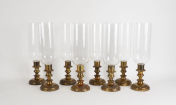 A SET OF EIGHT GILT-METAL CANDLESTICKS WITH GLASS STORM SHADES (8)