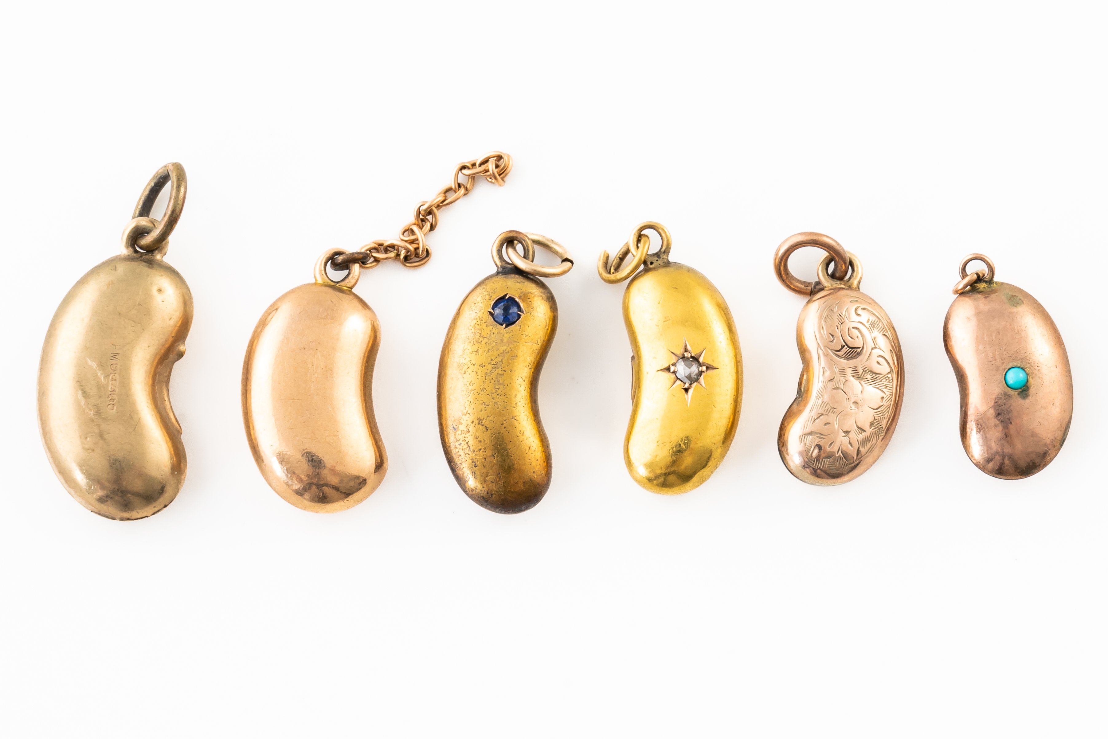 A GROUP OF SIX GOLD BEAN CHARMS (6)