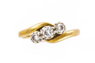 A GOLD AND DIAMOND THREE STONE CROSSOVER RING