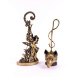 TWO ENGLISH PEERAGE BRASS DOOR STOPS: ONE MODELLED AS A BACCHANALIAN PUTTO, THE OTHER A FOX’S...