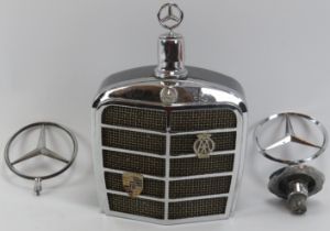 Automobilia: A vintage Mercedes Benz car grill drinks decanter flask and two car bonnet emblems,