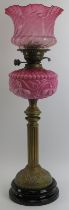 A Victorian brass and pink milk glass oil lamp with etched cranberry glass shade. Marked ‘Duplex.