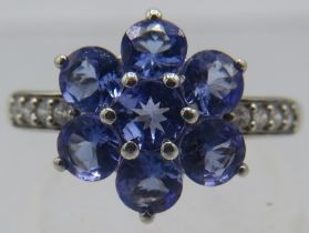 A 9ct white gold tanzanite daisy ring with white stone shoulders, size P. Approx weight 3.3 grams.