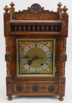 A Black Forest carved oak mantel clock, late 19th/early 20th century. The dial with silvered Roman