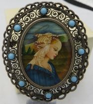 A hand painted miniature of a lady in a blue dress mounted in an oval pendant/brooch and set with