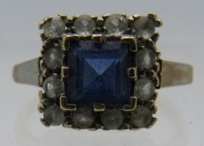 A 9ct yellow gold square set ring with centre sapphire, approx 5mm x 5mm surrounded with 12 white