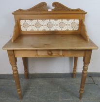 An antique pine washstand, having acanthus carved and scrolled cornice, above an inset tile back, on