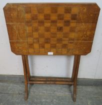 An Edwardian walnut folding table with chessboard top, on curved supports with turned stretchers.
