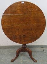 A George III medium oak tilt-top supper table, on a turned pedestal with splayed tripod supports.
