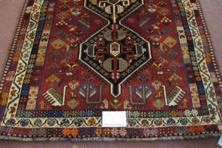 A good South West Persian Qashqai rug in central motif of three interlocking panels on a soft red