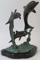 A bronze sculpture depicting dolphins leaping from the water, 20th century. Naturalistically