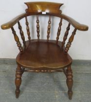 A turn of the century elm and beech captain’s chair with turned spindles, on canted turned