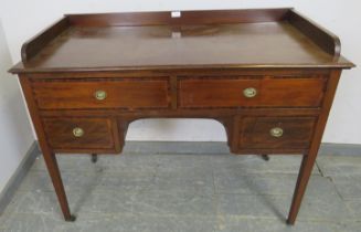 An Edwardian mahogany kneehole writing desk, having ¾ gallery above two long and two short