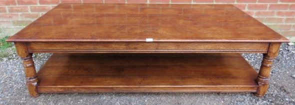 A large antique style solid oak coffee table, on turned and block supports united by an undertier