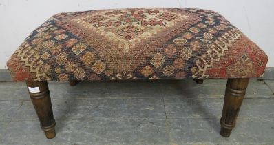 A contemporary footstool recovered with an antique Egyptian carpet, on turned tapering fruitwood