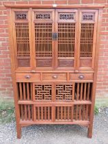 A vintage Chinese elm kitchen cupboard, having carved and pierced decoration and slatted doors