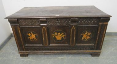 A late 17th/early 18th century panelled oak coffer, the front with carved frieze and marquetry