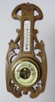 A late Victorian walnut aneroid barometer/thermometer of small proportions within an acanthus carved