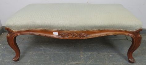A large 19th century walnut serpentine edged footstool, reupholstered in neutral material, the