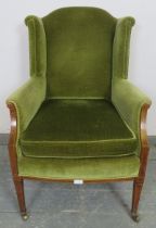 An Edwardian mahogany wingback armchair, upholstered in green velvet material, strung with satinwood