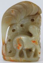 A Chinese pale green and russet jade carving of a deer amongst foliage, 20th century. 9 cm height.