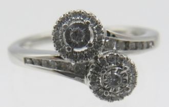 A 9ct white gold cross over ring with two diamond cluster and further channel set diamonds to the
