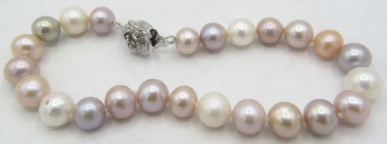 A pearl bracelet with pink, grey peach and white pearls with white metal flower shaped clasp. Approx