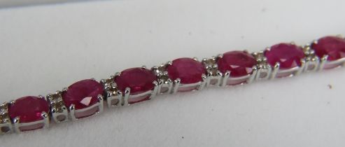 An 18ct white gold line bracelet set with rubies interspersed with two small diamonds, double safety