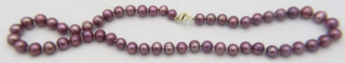 An 18" approx dark purple pearl necklace with yellow metal lobster clasp. Approx weight 35.7