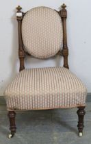 A late Victorian walnut bedroom chair, having bun finials and reeded uprights, upholstered in period