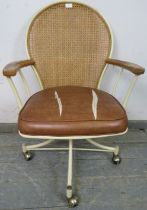 A mid-century swivel desk chair, having a bergère back and elm armrests on a steel frame painted