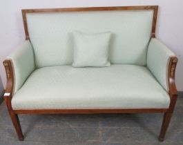 An antique mahogany love seat in the French taste, having applied guilt metal mounts, re-upholstered