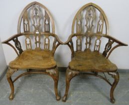A pair of well-carved vintage elm elbow chairs in a Gothic taste, the steeple backs having carved