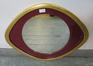 A circular bathroom wall mirror, within an elliptical ceramic parcel gilt and claret surround. H49cm